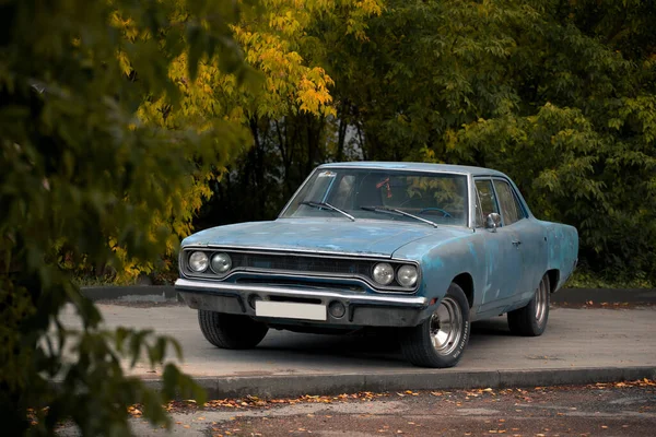Eski Amerikan kaslı arabası Plymouth Belvedere 1970 Sonbahar parkında turuncu ağaçlarla kaplı yolda