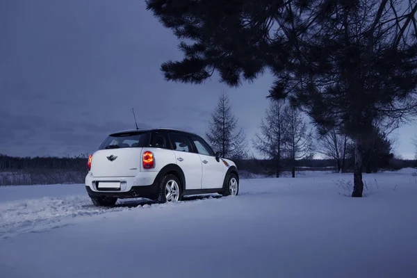 British Compact Car Mini Countryman Dark Winter Forest Snow Road Stock Image