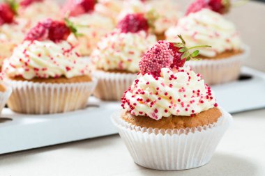 Kremalı ve çilekli kapkekler, yakın plan. 