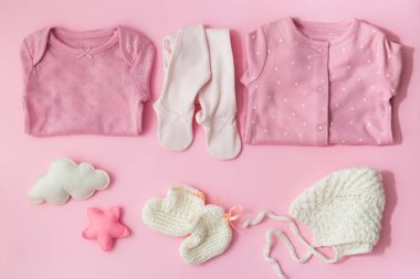 Pembe arka planda bebek kıyafetleri ve aksesuarlar