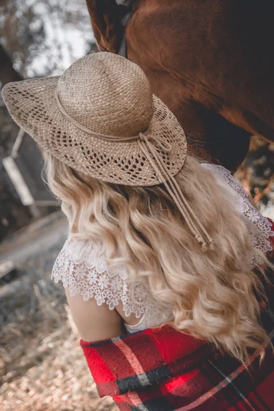 年轻的金发女郎戴着帽子与马同行 — 图库照片