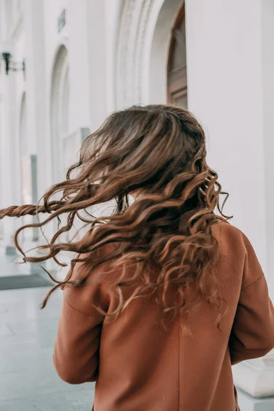The beautiful blonde lady with curly hair. The back view of a girl. Woman walking down the street. Traveler, summer fashion trend