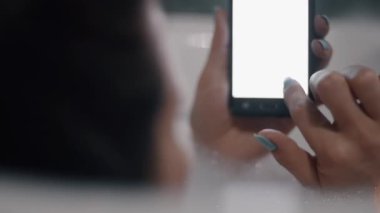 Akıllı telefon kullanan genç kadın banyo