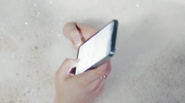 Küvet köpük banyosu Smartphone kullanarak, kadında yakın çekim