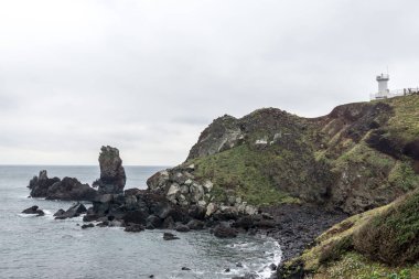 Seopjikoji ışık ev görünümü kıyı çizgisinde birçok sivri taşlarla. Seopjikoji ünlü doğal dönüm noktası Jeju Adası, Güney Kore olduğunu