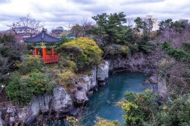 Yongyeon gölet ve çevresindeki rock sahne. Yongyeon gölet yakınlardaki dağ su okyanusa bağlanır. Jeju Adası, Güney Kore'de alınan