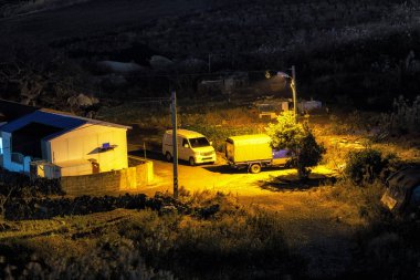 Uzun boylu sazlık tarafından çevrili sokak ışık tarafından aydınlatılmış bir küçük kırsal ev gece görünümü. 6th Aralık 2018 alınan. Jeju Adası, Güney Kore