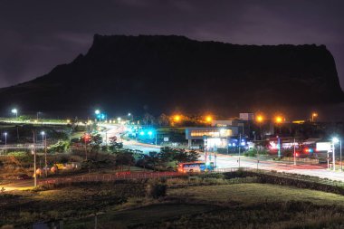 Seongsan Ilchulbong en yüksek ön planda sokak ışıkları ile gece görüntülendi. 6th Aralık 2018 alınan. Jeju Adası, Güney Kore