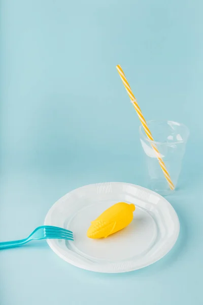 Sosyal içerik. Mavi arka planda çatalı olan tek kullanımlık tabaklarda plastik yiyecekler. Boşluğu kopyala.