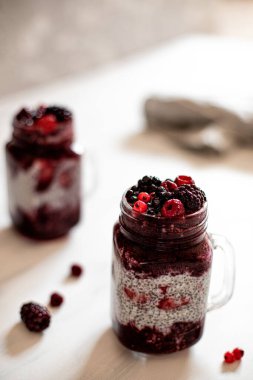 Beyaz arka planda böğürtlen püresi ve chia tohumlu iki kupa..