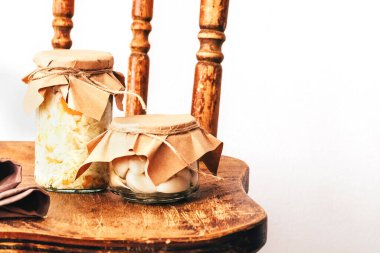 Geri dönüşümlü malzemelerden elde edilen kağıtlarla kaplı şeffaf cam kavanozlarda bulunan sebzeler. Sarımsak, lahana. Beyaz arka planda ahşap bir arka planda. Boşluğu kopyala