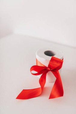 Beyaz arka planda kırmızı fiyonklu tuvalet kağıdı..