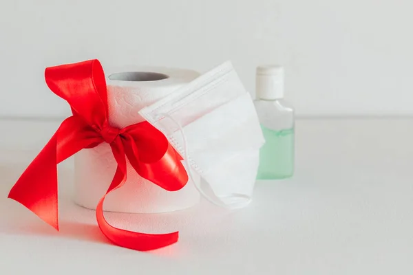 toilet paper with a red bow on a white background. Sanitizer. White medical mask