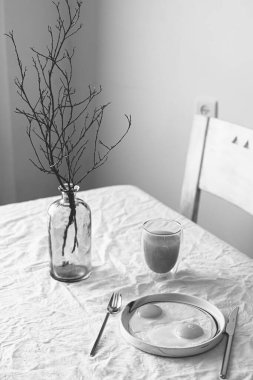 Yağda yumurta. Beyaz masa. Dallı mavi vazo. Durgun hayat. meyve suyu