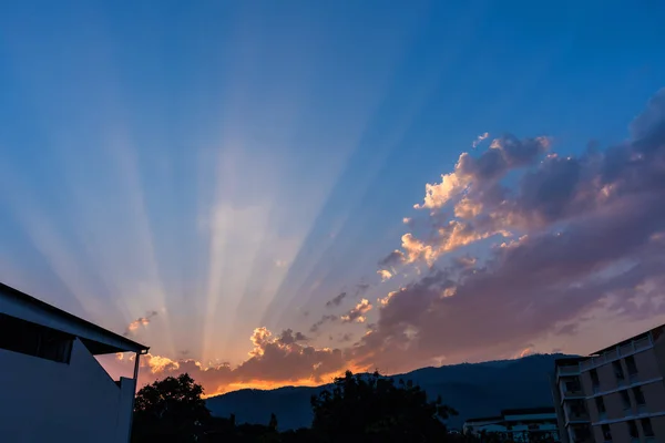 背景下的太阳黄昏射线 的建筑与山脉意象 — 图库照片