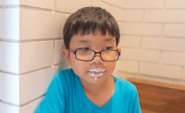 Ağız özensiz olana genç yakışıklı çok güzel Asyalı çocuk köpüklü süt İçecek.