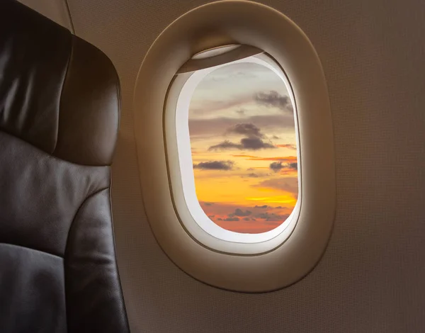 image of aircraft seat and plane window with beautiful blue sky in background.
