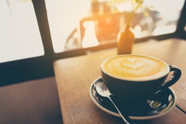  Ahşap masa üzerinde fincan latte kahve sanatı.