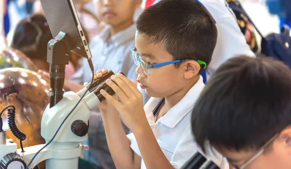 Asiatico ragazzo uso microscopio per vedere piccolo vivente cosa . — Foto Stock