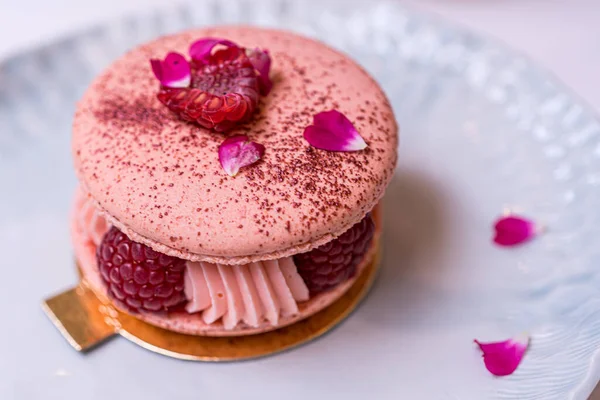 Beautiful Pink Raspberry Macaron cookies on blue plate. Healthy food. Blue table background. Top view.