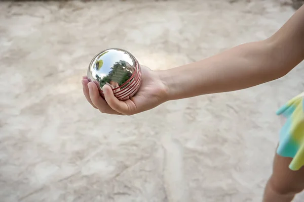 Una ragazzina che gioca a bocce. boule di metallo su uno sfondo leggero. Stile vintage retrò. Popolare francese gioco all'aperto. — Foto Stock