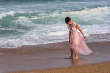 Atlantik Okyanusu sahilinde yürüyen genç bir kadın. Güzel model. Yumuşak arkaplan