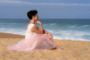 Sahilde oturan romantik genç kız. Güzel model. Yumuşak arkaplan