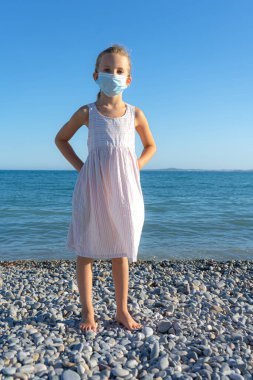 Yumuşak odaklanma. Sahilde koruyucu maske takan bir kız.