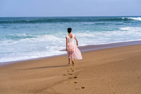 Uma jovem mulher a caminhar na praia do oceano Atlântico. Bonito modelo. Fundo suave — Fotografia de Stock