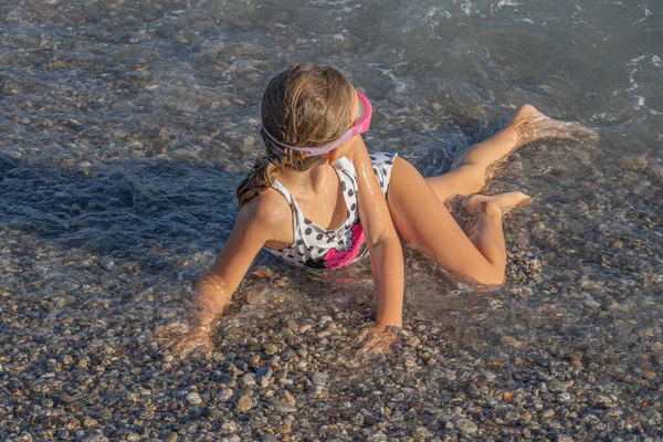 Mała dziewczynka pływa w falach na wybrzeżu — Zdjęcie stockowe
