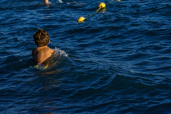 A kisfiú úszik a hullámokban a Földközi-tenger partján. — Stock Fotó