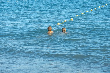Çocuklar Akdeniz 'de yüzerler. Erkek ve kız kardeş birlikte yüzüyor.