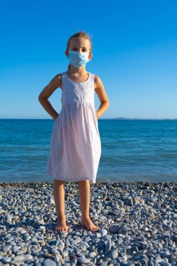 Yumuşak odak arkaplanı. Sahilde koruyucu maske takan bir kız.