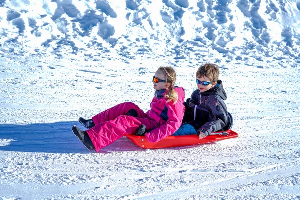 Dos niños felices bajando en trineo por las colinas en un día de invierno. —  Fotos de Stock