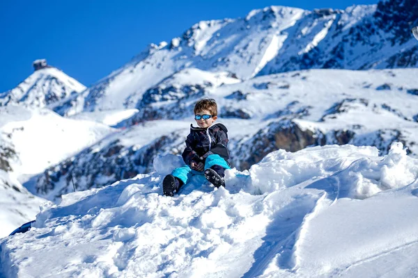 Νεαρό αγόρι κάθεται στο χιονισμένο βουνό — Φωτογραφία Αρχείου