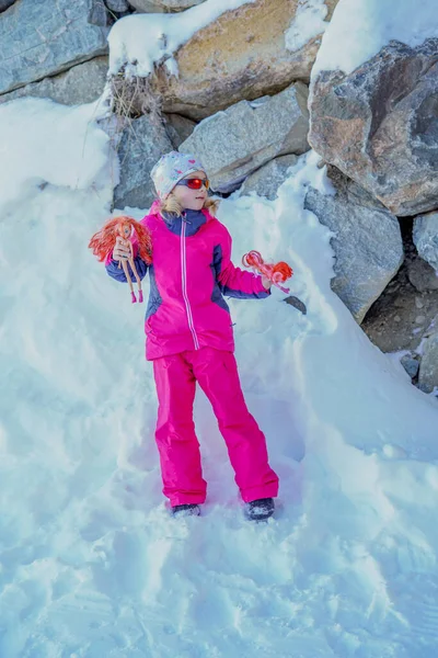 LAlpe DHuez, França 30.12.2019 Retrato de inverno ao ar livre da menina bonitinha nos óculos de sol e vestindo roupas de esqui. Menina andando com bonecas . — Fotografia de Stock