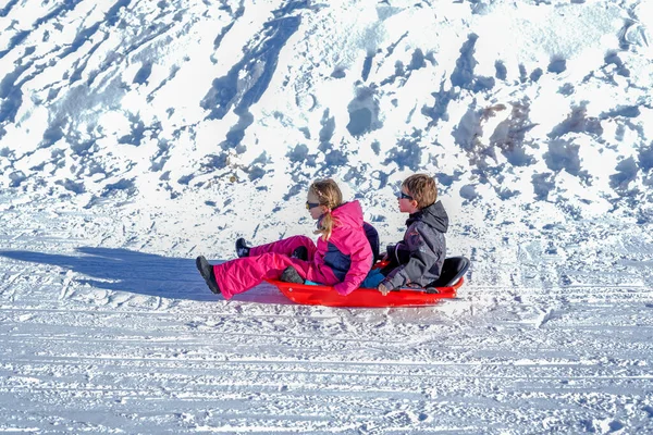 Δύο χαρούμενα παιδιά να κατεβαίνουν στους λόφους μια χειμωνιάτικη μέρα. — Φωτογραφία Αρχείου