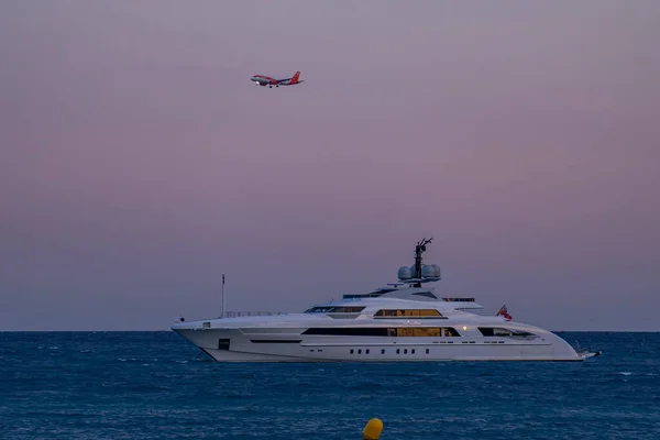 Cagnes-sur-mer, France 22.07.2020 Modern luxury yacht on the sea and flying passenger plane later evening, great design for any purposes — Stock Photo, Image