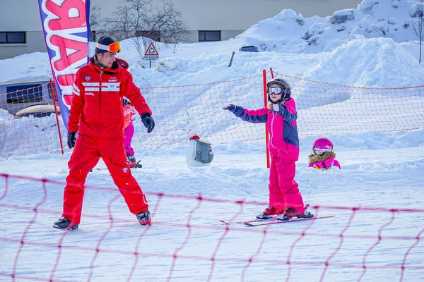 LAlpe DHuez, France 02.01.2019 Professional ski instructor is teaching a child to ski on a sunny day on a mountain slope resort. — Stock Photo, Image