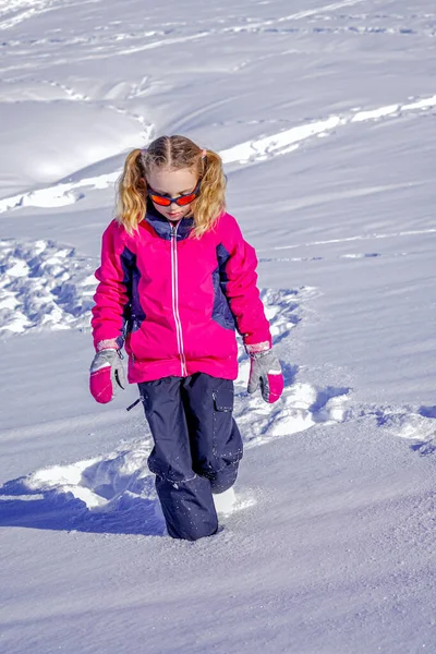 Όμορφο κορίτσι φοράει ένα ροζ μπουφάν του σκι παίζει και τρέχει σε ένα χιονισμένο χειμερινό πάρκο. Μαλακό φόντο εστίασης — Φωτογραφία Αρχείου