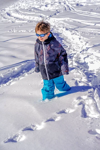 Νεαρό αγόρι με γυαλιά ηλίου που περπατάει στο χιόνι — Φωτογραφία Αρχείου