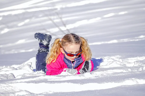 Μαλακό φόντο εστίασης. Νεαρή κοπέλα ξαπλωμένη στο χιόνι με χειμωνιάτικα ρούχα. — Φωτογραφία Αρχείου
