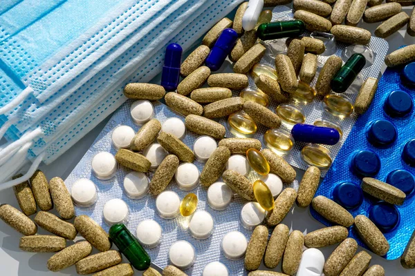 Närbild av medicinska skyddsmasker med olika piller över ljusgrå bakgrund — Stockfoto