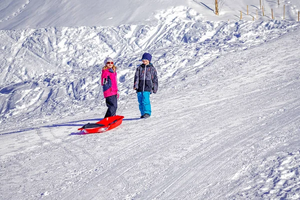 어느 겨울날 언덕에서 한가로이 쉬고 있는 즐거운 두 아이. — 스톡 사진