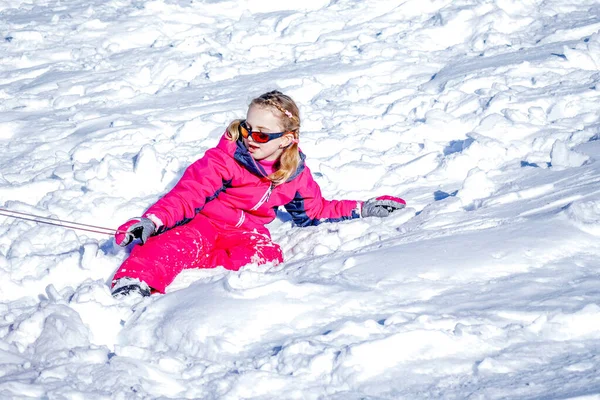 Giovane ragazza seduta sulla montagna di neve e giocare con la palla di neve . — Foto Stock