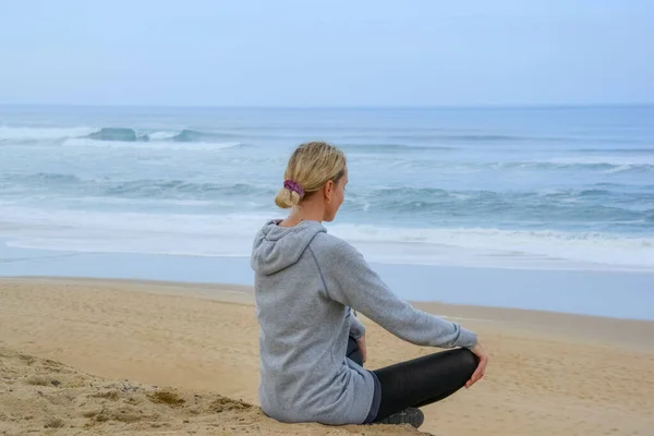 Peaceful healthy and fit young woman meditating on the beach. Yoga in the beach. Woman meditating in lotus pose. — Stock Photo, Image