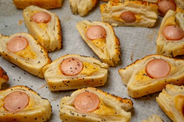 Sosisli çörek ve hardallı puf böreği. Lezzetli atıştırmalıklar, tapas, kahvaltı, kurabiye kağıdındaki aperatifler. Üst görünüm