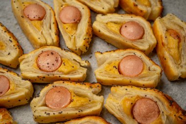 Sosisli çörek ve hardallı puf böreği. Lezzetli atıştırmalıklar, tapas, kahvaltı, kurabiye kağıdındaki aperatifler. Üst görünüm