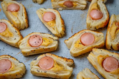 Sosisli çörek ve hardallı puf böreği. Lezzetli atıştırmalıklar, tapas, kahvaltı, kurabiye kağıdındaki aperatifler. Üst görünüm