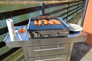 Mangal için ızgarada kaplan karidesi pişiriyorum. Teras göl manzaralı arka planda ızgara. 